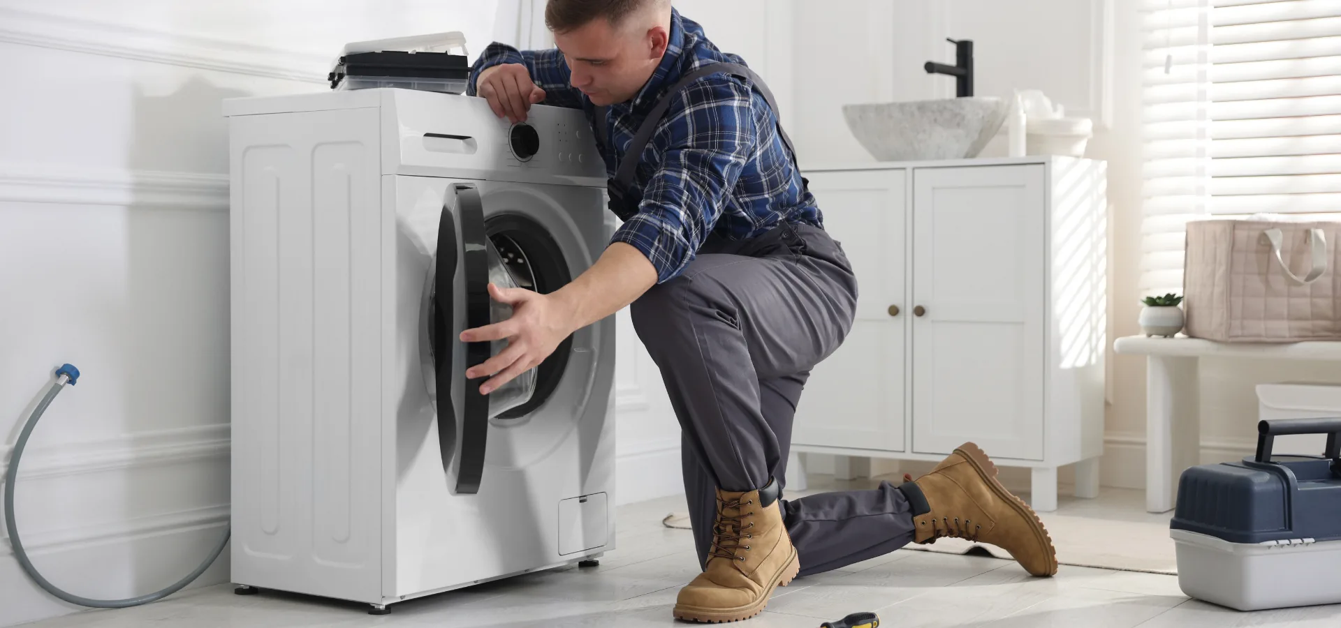 Tehnician reparând o mașină de spălat acasă la client